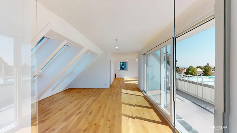 Helles, leeres Zimmer mit Holzboden, großen Dachfenstern und Zugang zu einem Balkon.