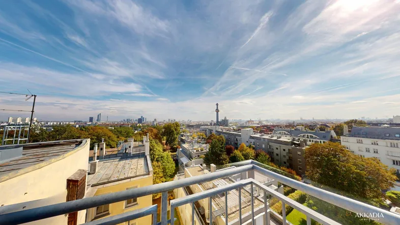 Weitläufiger Blick über die Stadt von einem Balkon mit blauem Himmel und Wolken.