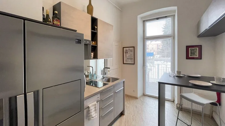 Helle Küche mit großem Kühlschrank, Bartresen und einem Fenster mit Blick nach draußen.