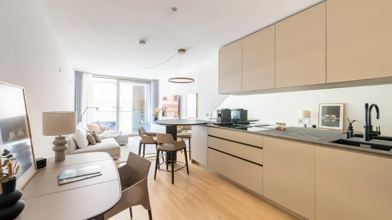 Helle, offene Wohnküche mit modernem Design, Holzboden und Zugang zum Balkon.