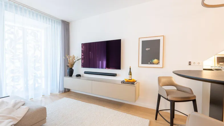 Helles Wohnzimmer mit modernem TV-Möbel, bequemer Couch und einem kleinen Barbereich.