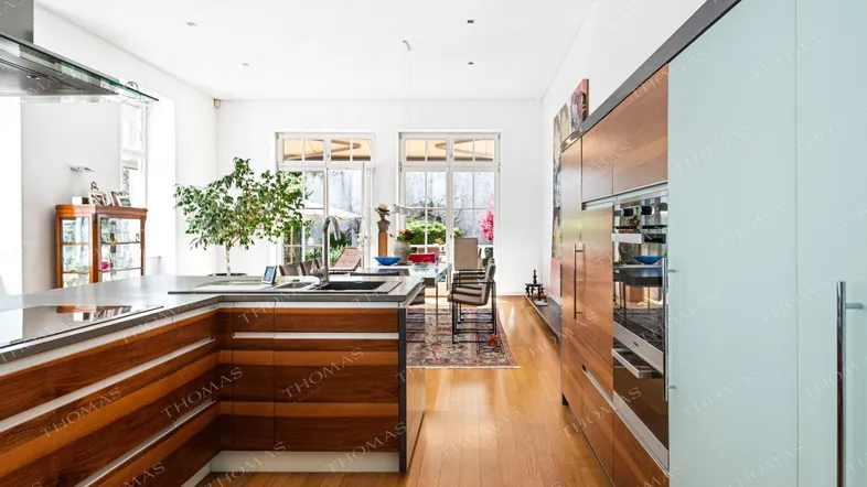 Moderne offene Küche mit Holzelementen, Kochinsel und Essbereich im Hintergrund.