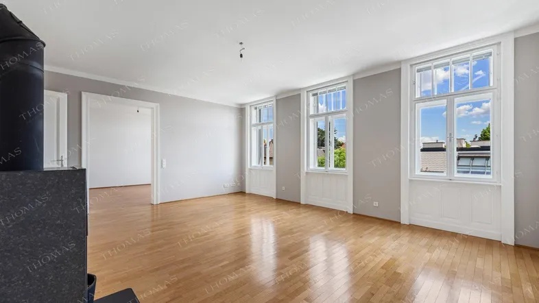 Helles Wohnzimmer mit Holzboden, modernen Fenstern und einem stilvollen Kaminofen.