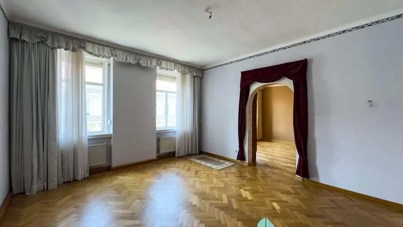 Geräumiges Wohnzimmer mit Fischgrätparkett und dekorativem Türbogen, bereit zur individuellen Gestaltung.