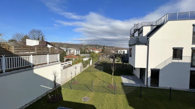 Moderne Wohnanlage mit gepflegtem Rasenbereich und weitem Blick unter blauem Himmel.