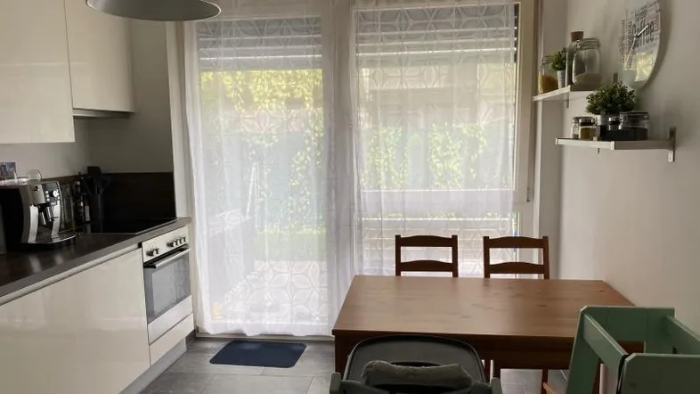 Moderne Küche mit Essbereich, weißen Schränken und Zugang zur Terrasse.