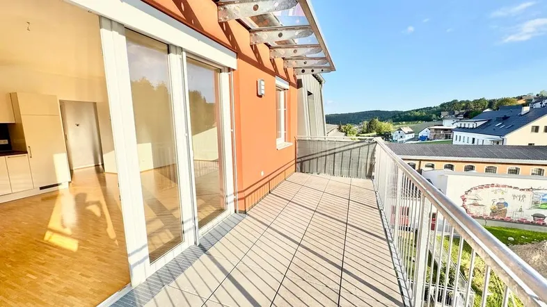 Geräumiger Balkon mit Fliesenboden, Glasüberdachung und weitem Blick ins Grüne.