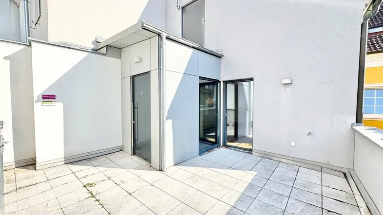 Geräumige Dachterrasse mit Fliesenboden und Zugang zu den Innenräumen, ideal für Entspannung im Freien.