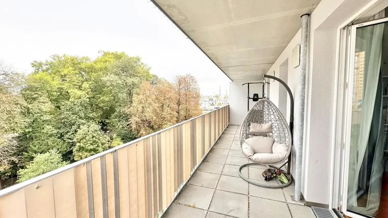 Langer Balkon mit Hängesessel und Blick ins Grüne, ideal zum Entspannen im Freien.