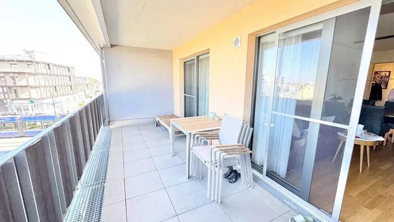Geräumiger Balkon mit Fliesenboden, Sitzgelegenheiten und Blick auf die Stadt.
