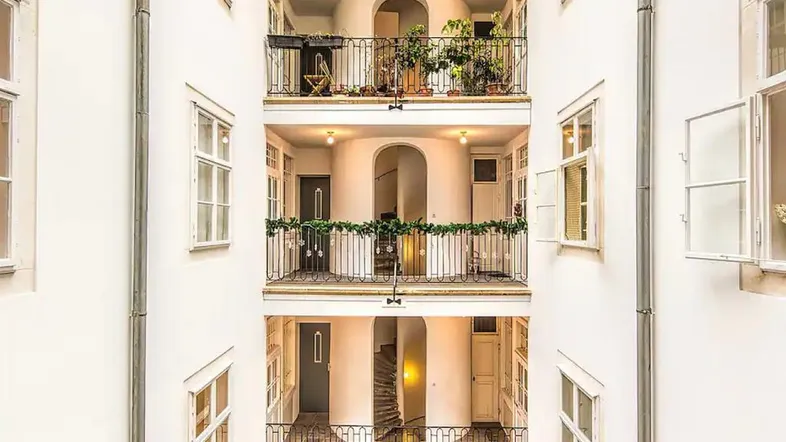 Blick in einen hellen Innenhof mit mehreren Balkonen und einer eleganten Wendeltreppe.