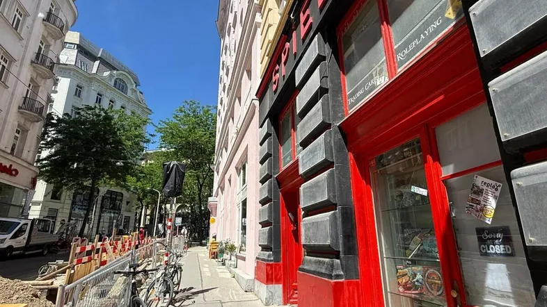 Blick auf eine belebte Stadtstraße mit einem Gebäude, das ein Geschäft mit roter Fassade beherbergt.