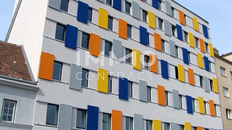 Modernes Mehrfamilienhaus mit farbigen Fensterläden und Geschäftsflächen im Erdgeschoss.