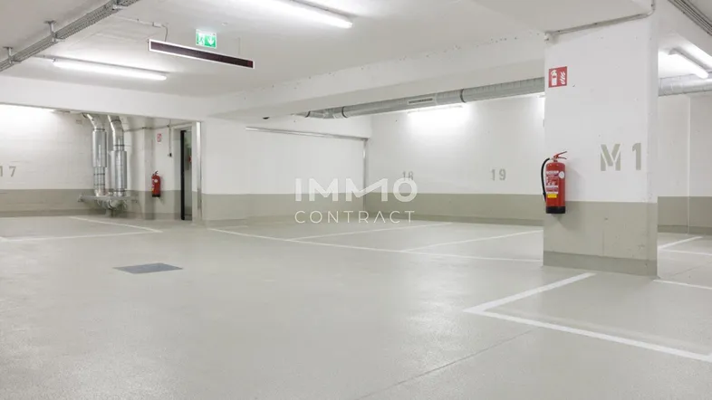 Helle Tiefgarage mit markierten Stellplätzen, guter Beleuchtung und sichtbaren Installationen.