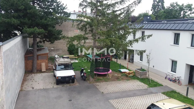 Hofbereich mit Parkplätzen, einem Trampolin, einem Gartenhaus und einer kleinen Grünfläche.