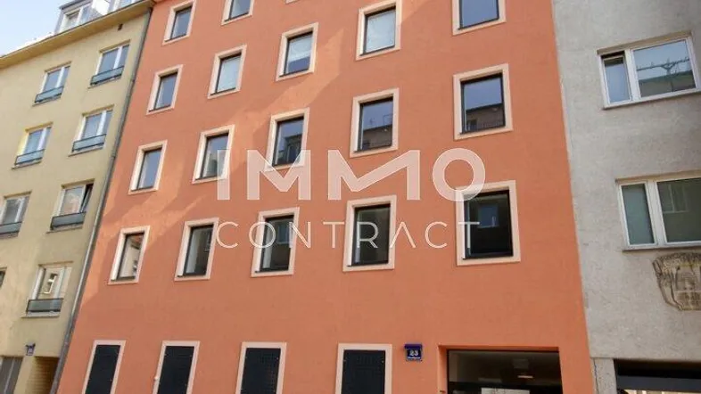 Mehrstöckiges Wohngebäude mit orangefarbener Fassade und zahlreichen Fenstern in einer städtischen Umgebung.