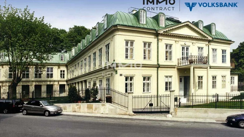 Elegantes historisches Gebäude mit klassischer Fassade, Mansarddach und schmiedeeisernem Zaun.