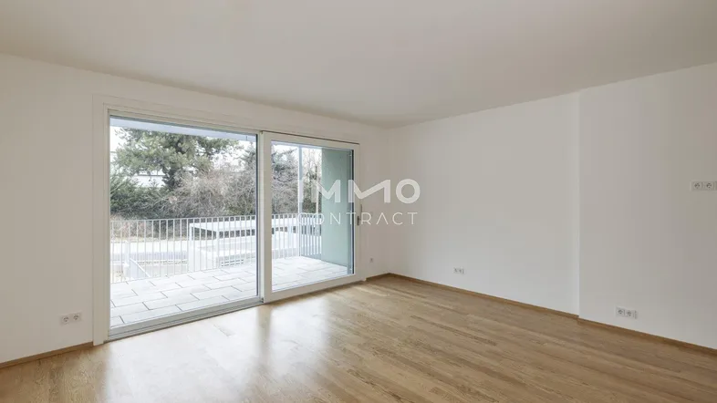 Helles Zimmer mit Holzboden und Zugang zu einer Terrasse oder einem Balkon.