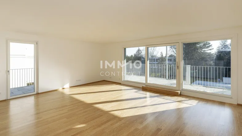 Helles Wohnzimmer mit Holzboden und großen Fenstern, die Zugang zu einem Balkon bieten.