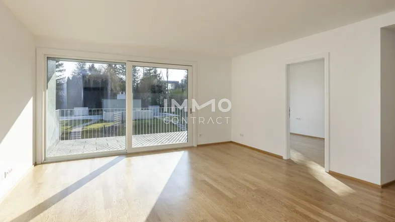 Helles Wohnzimmer mit Holzboden und Zugang zu einem Balkon, ideal für entspannte Stunden.