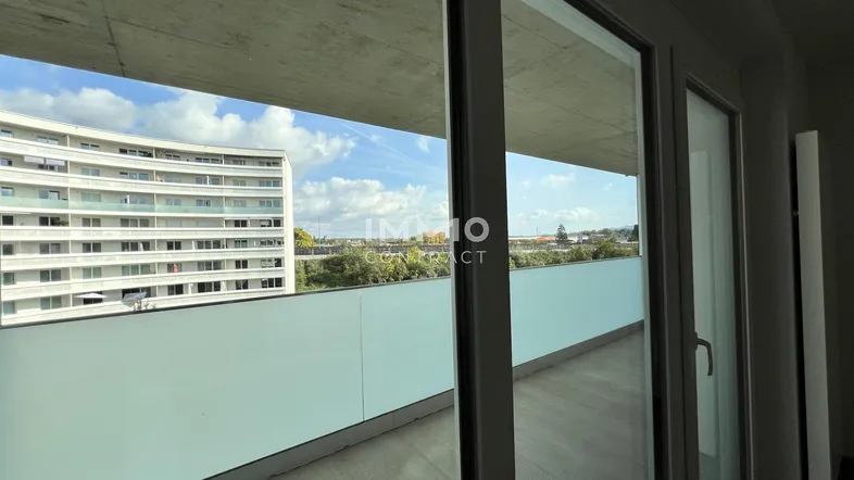 Geräumiger Balkon mit Blick auf die umliegenden Gebäude und den Himmel.