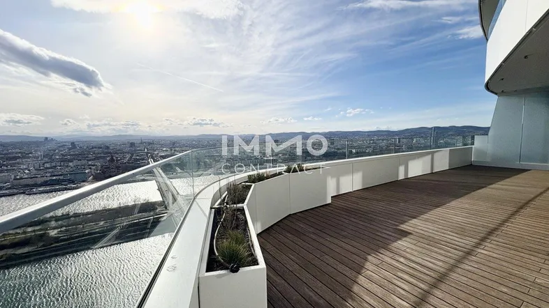 Geräumige Dachterrasse mit Holzboden, Glasgeländer und weitem Blick über die Stadt und den Fluss.