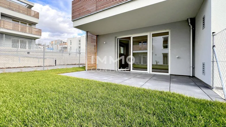 Moderne Terrasse mit direktem Zugang zum Garten und Blick auf das Gebäude.