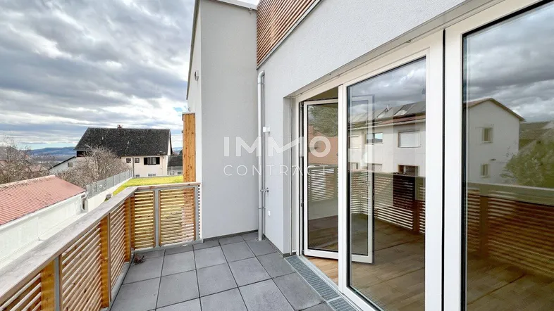 Moderner Balkon mit Fliesenboden und Holzgeländer, bietet einen Blick auf die Umgebung.
