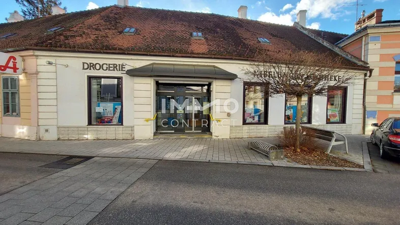 Gebäudeansicht einer Drogerie mit Schaufenstern und Eingangsbereich an einem sonnigen Tag.