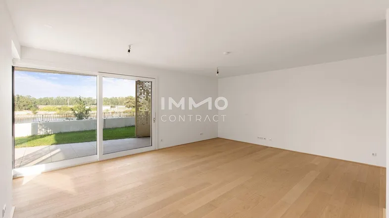Helles Wohnzimmer mit Parkettboden und großzügigem Zugang zu einer Terrasse oder Gartenfläche.