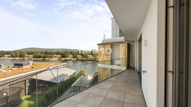 Langer Balkon mit Glasgeländer und weitem Blick auf den See und die umliegende Landschaft.