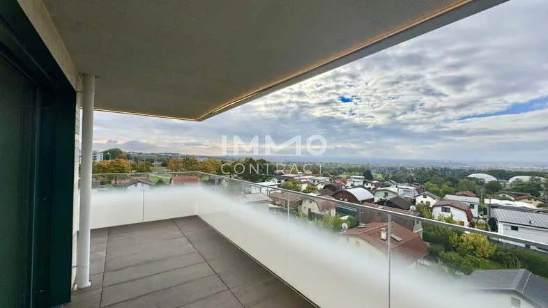 Geräumiger Balkon mit Fliesenboden und weitem Blick über die Stadt und die umliegende Landschaft.
