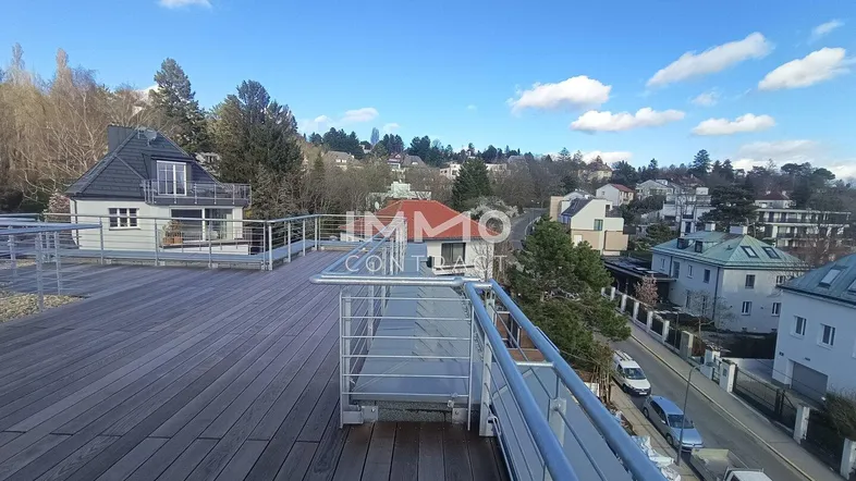 Geräumige Dachterrasse mit Holzboden und Metallgeländer, bietet einen weiten Blick über die Umgebung.