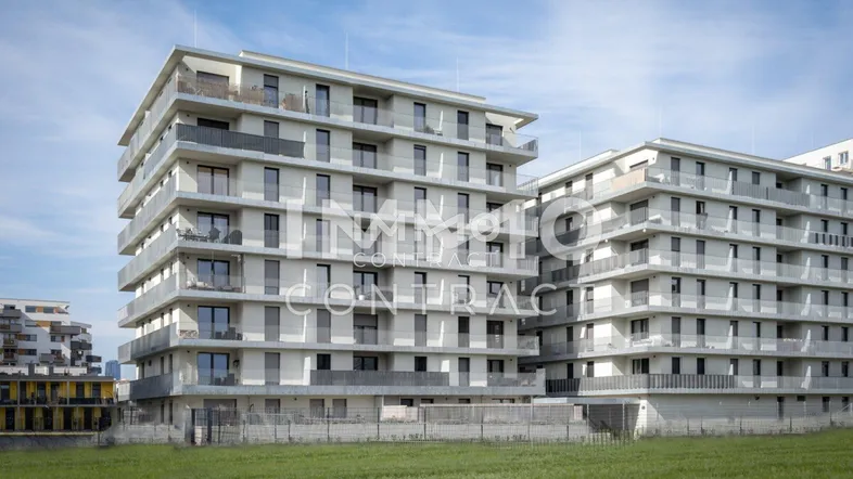 Neubauwohngebäude mit mehreren Balkonen und einer weiten Grünfläche im Vordergrund.