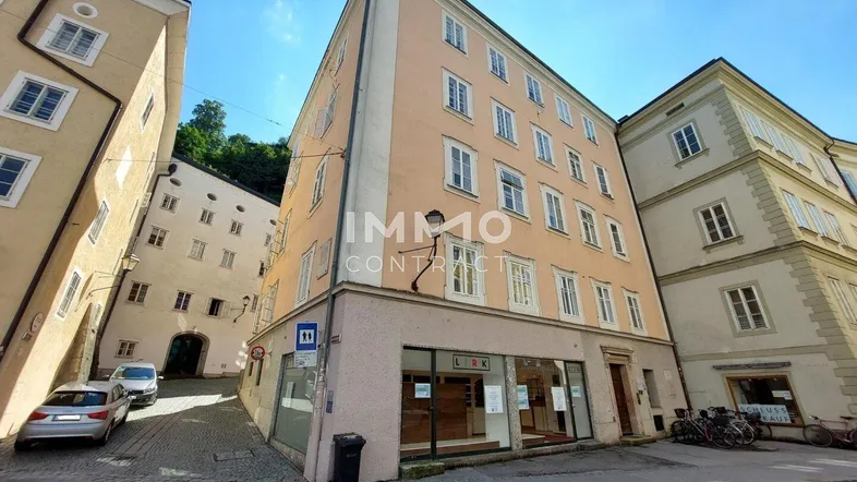Historisches Gebäude mit mehreren Stockwerken und Ladenlokal im Erdgeschoss in einer städtischen Gasse.
