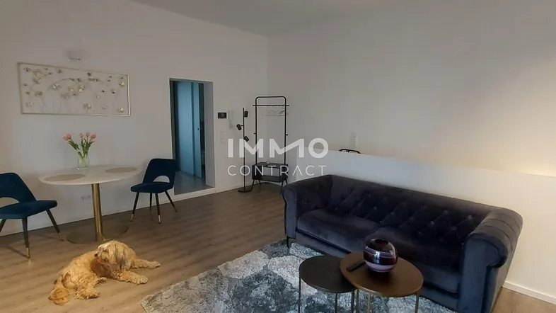 Heller Wohn- und Essbereich mit bequemer Couch, Esstisch und Holzboden, ideal für entspannte Stunden.