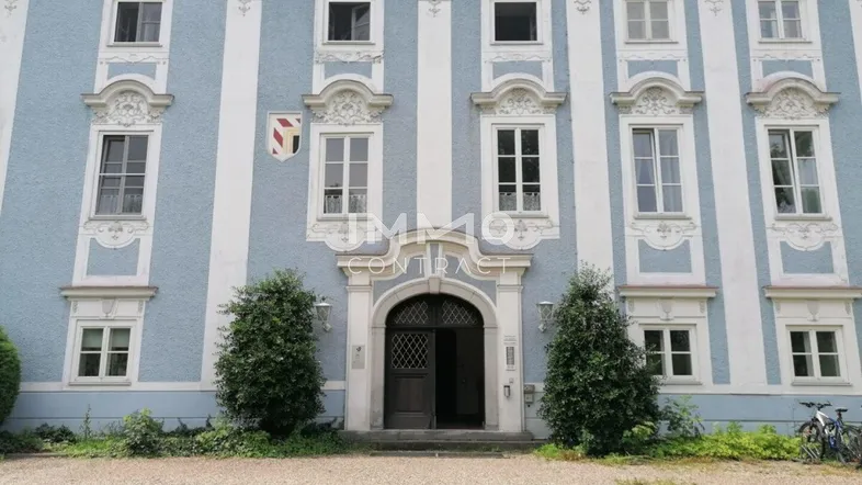 Elegante Fassade eines historischen Gebäudes mit hellblauen und weißen Elementen und großen Fenstern.