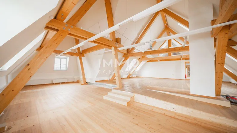 Geräumiger Dachbodenraum mit sichtbaren Holzbalken und hellem Holzfußboden, ideal für vielfältige Nutzung.