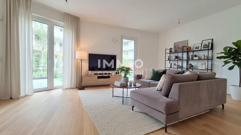 Helles Wohnzimmer mit modernem Sofa, Holzboden und Zugang zu einer Terrasse oder Gartenfläche.