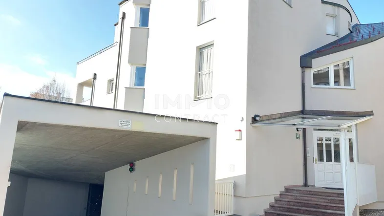 Eingangsbereich des Gebäudes mit überdachtem Carport und Treppe zum Haupteingang.
