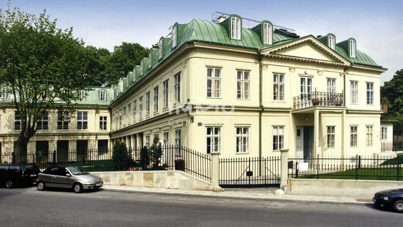 Elegantes historisches Gebäude mit klassischer Architektur, grünen Dächern und schmiedeeisernem Zaun.