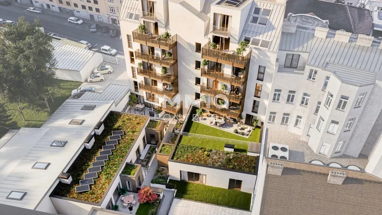 Luftaufnahme eines modernen Wohnkomplexes mit begrünten Dächern, Balkonen und Innenhofgärten.