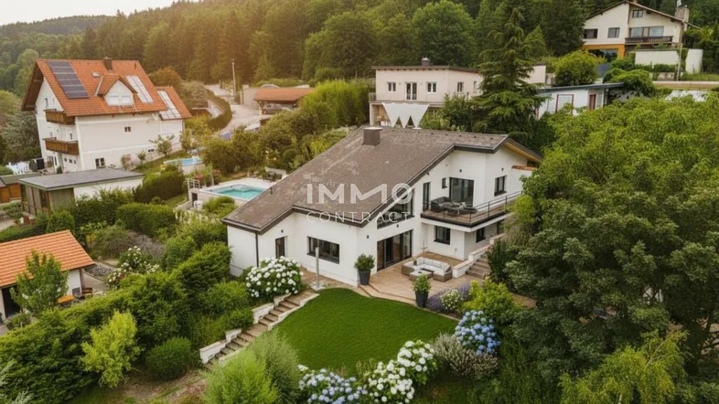 Luftaufnahme des modernen Hauses mit Garten, Pool und umliegender grüner Landschaft.
