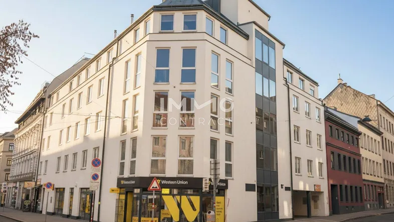 Modernes Eckgebäude mit großen Fenstern und Geschäftsflächen im Erdgeschoss an einer Stadtstraße.