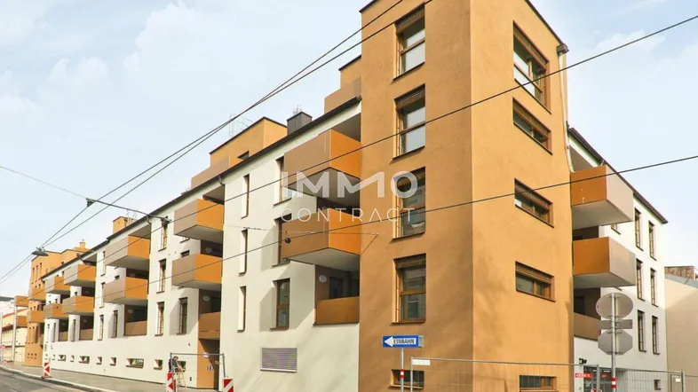 Modernes Mehrfamilienhaus mit markanter Fassade, zahlreichen Balkonen und großen Fenstern.