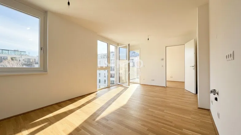 Helles und geräumiges Zimmer mit Parkettboden und großen Fenstern, die viel Sonnenlicht hereinlassen.