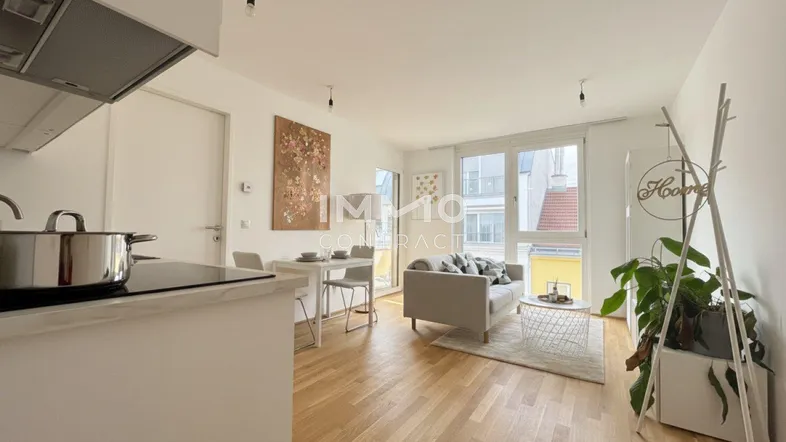 Helles, offenes Wohnzimmer mit integrierter Küche, Parkettboden und großen Fenstern.