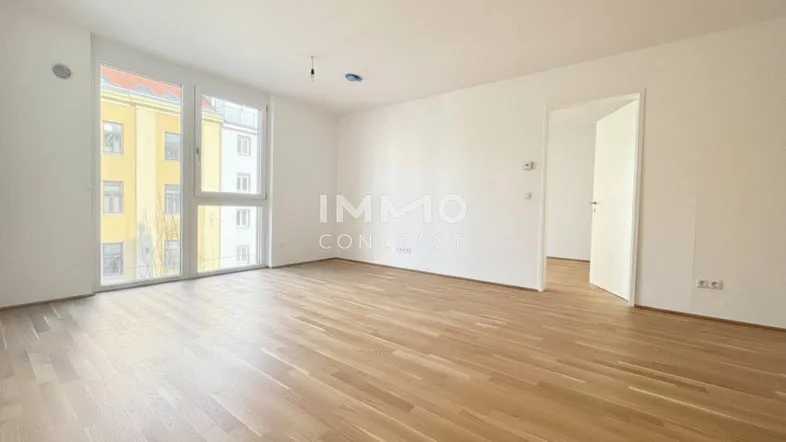Heller, geräumiger Wohnbereich mit großen Fenstern, die viel Tageslicht hereinlassen, und hochwertigem Parkettboden.