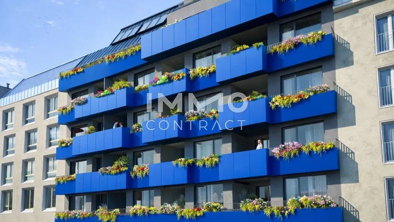 Modernes Mehrfamilienhaus mit blauen Balkonen und Blumenkästen in städtischer Umgebung.