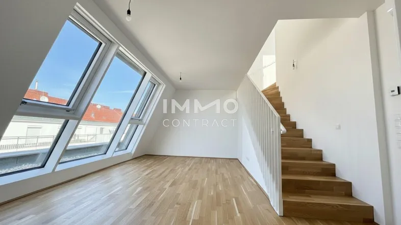 Heller Wohnbereich mit großen Dachfenstern, Parkettboden und offener Treppe zum Obergeschoss.